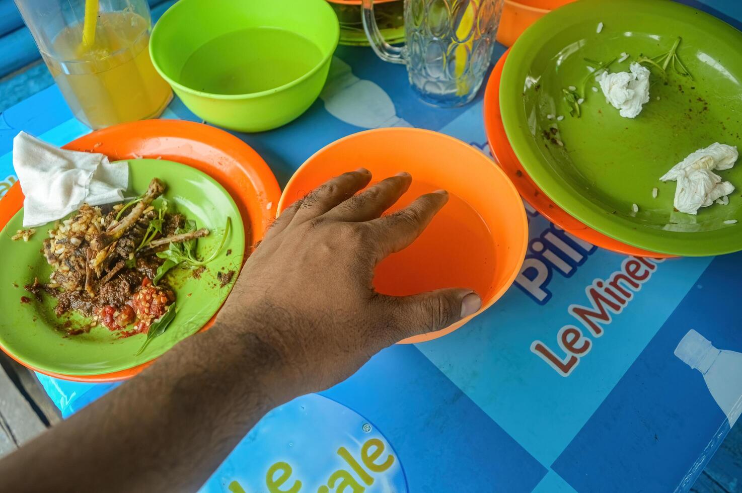 ein Schüssel gefüllt mit sauber Wasser zum Waschen Hände im ein traditionell Restaurant auf das Insel von Madura mit etwas übrig bleiben Essen um Es, Indonesien, 17 November 2023. foto