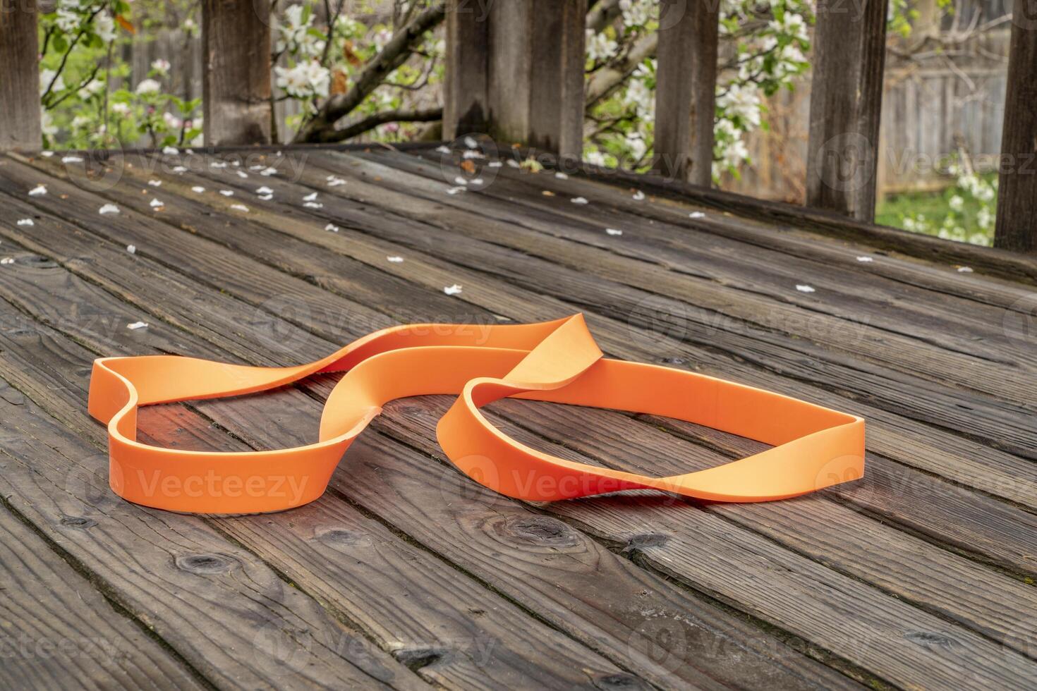 schwer Pflicht Widerstand Übung Band zum Fitness und Rehabilitation auf hölzern Hinterhof Deck, Frühling Landschaft foto