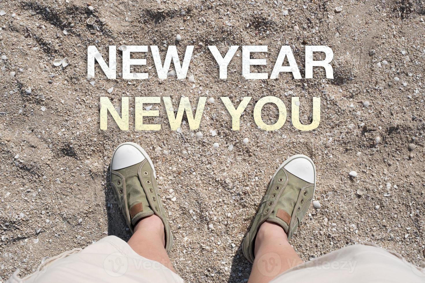 Luftaufnahme des neuen Jahres neues Wort auf Sand mit Menschenfuß foto