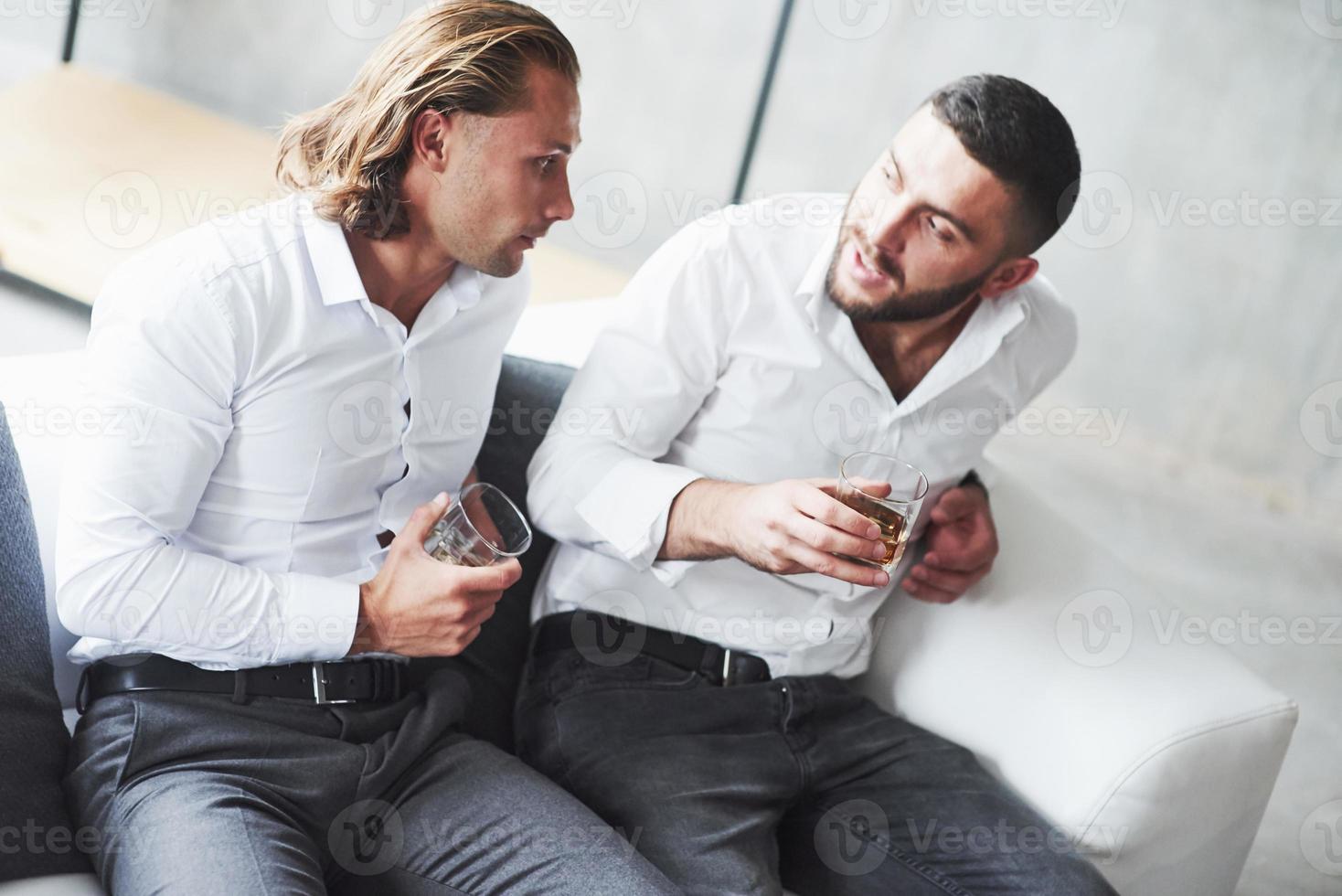 zwei Teamkollegen unterhalten sich in der Pause und trinken Whisky foto