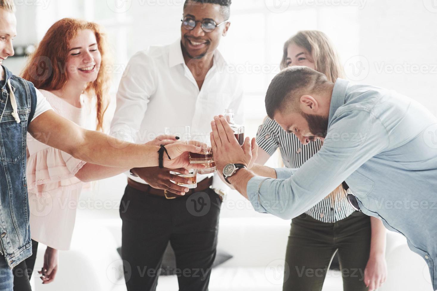 Der kurzhaarige, bärtige Typ beschließt, heute viel zu trinken. Teamkollegen trinken Whisky und lachen wegen des erfolgreichen Deals foto