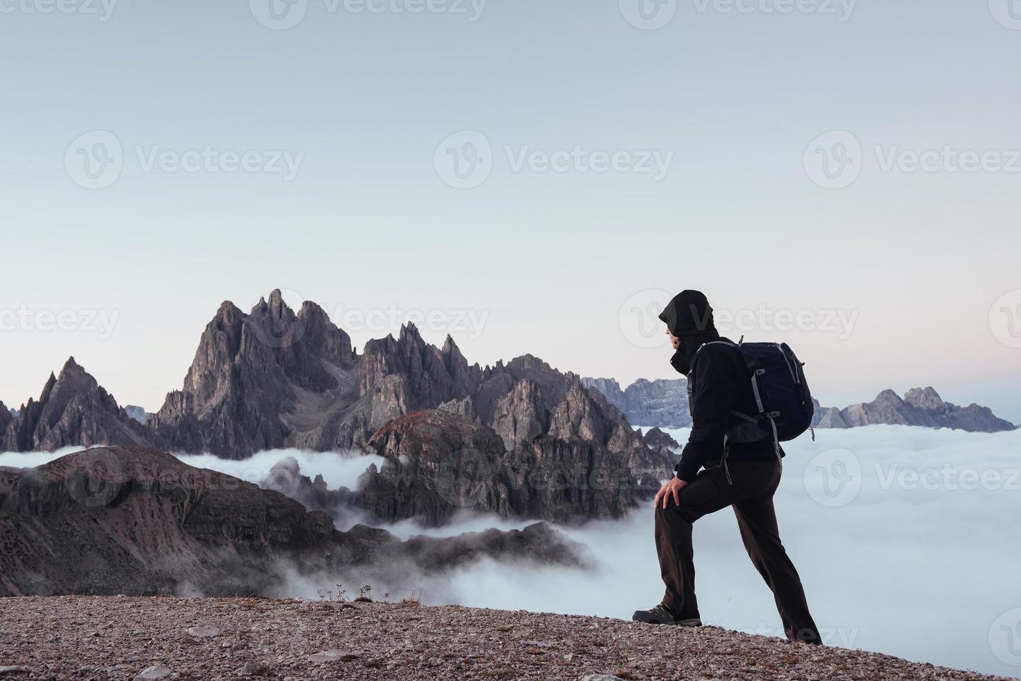 Erwachsener Tourist, der am Rand des Hügels walzt und zusieht und tolle Berge im Hintergrund? foto