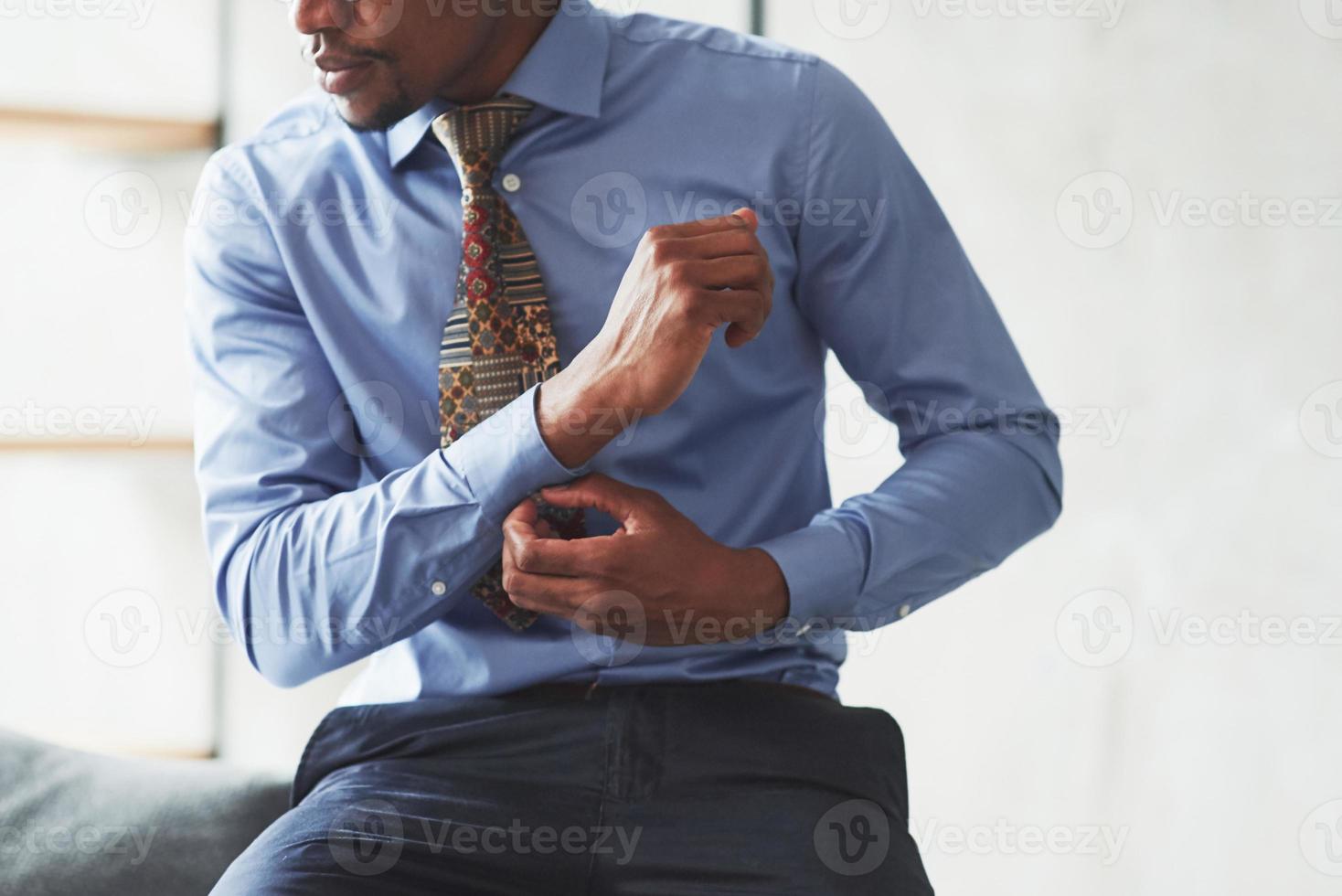 Foto von einem schwarzen, stilvollen Mann, der Kleidung trägt und sich auf die Arbeit vorbereitet