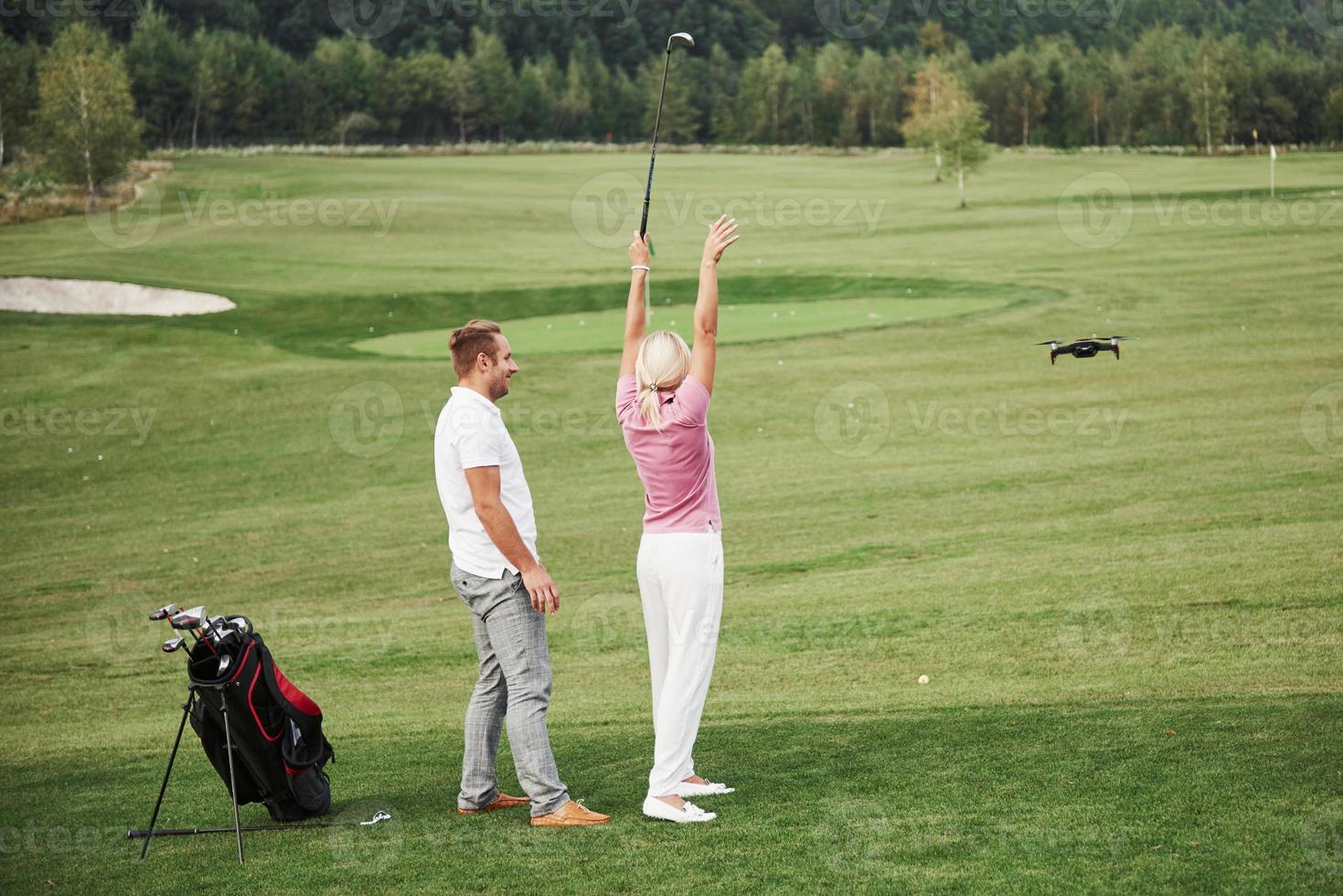 Gruppe stilvoller Freunde auf dem Golfplatz lernen ein neues Spiel zu spielen foto