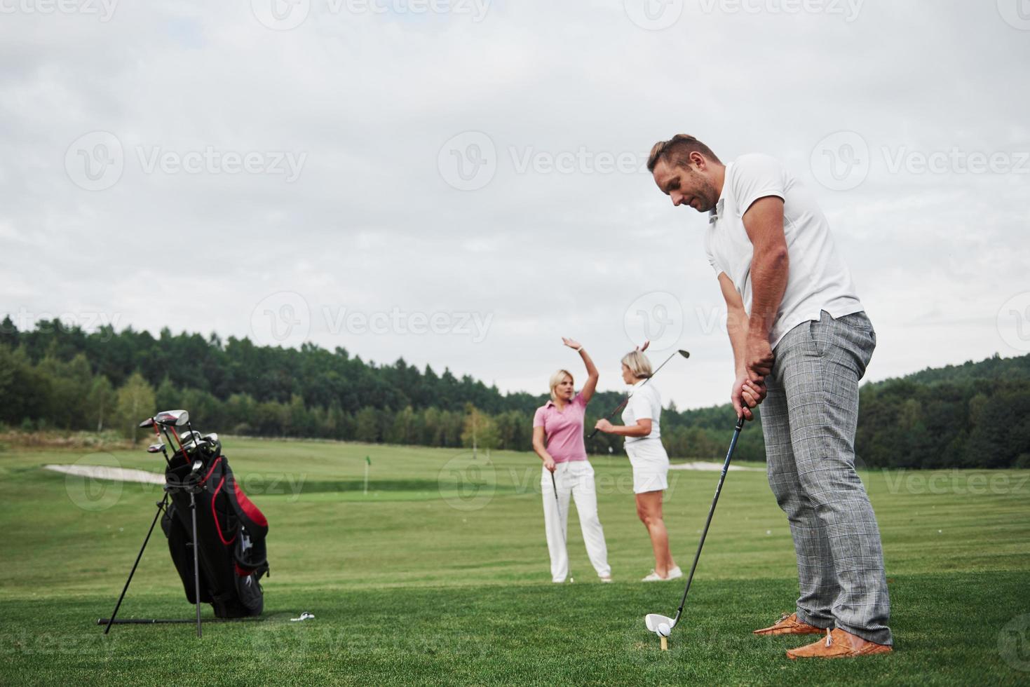 Gruppe stilvoller Freunde auf dem Golfplatz lernen ein neues Spiel zu spielen foto