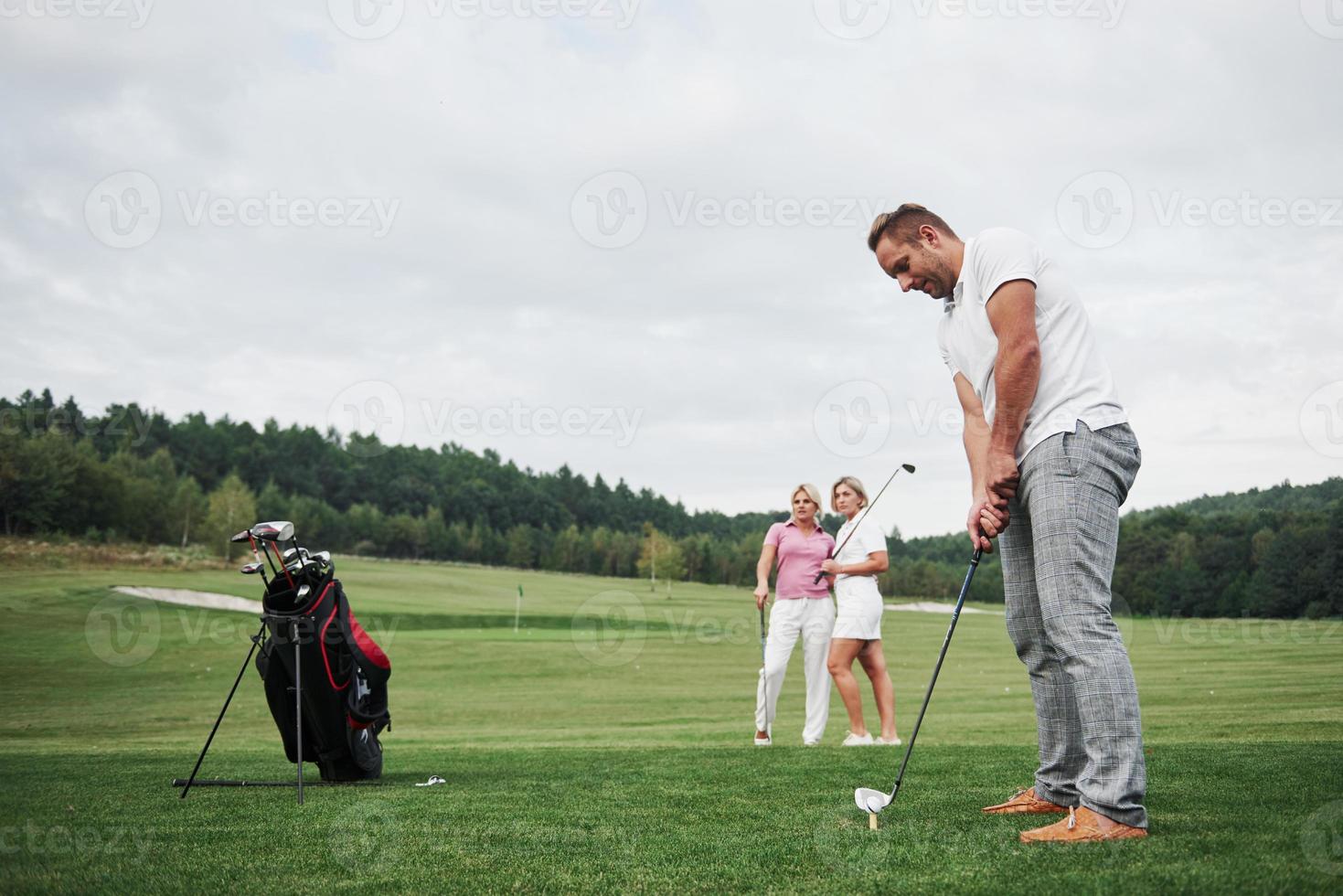Gruppe stilvoller Freunde auf dem Golfplatz lernen ein neues Spiel zu spielen foto