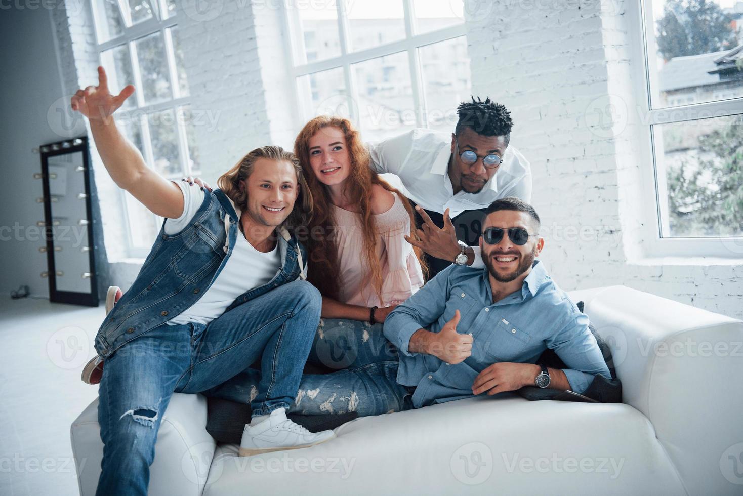 jeder hat seine eigene Geste. schöne Leute sitzen auf dem Sofa mit Fenstern im Hintergrund foto