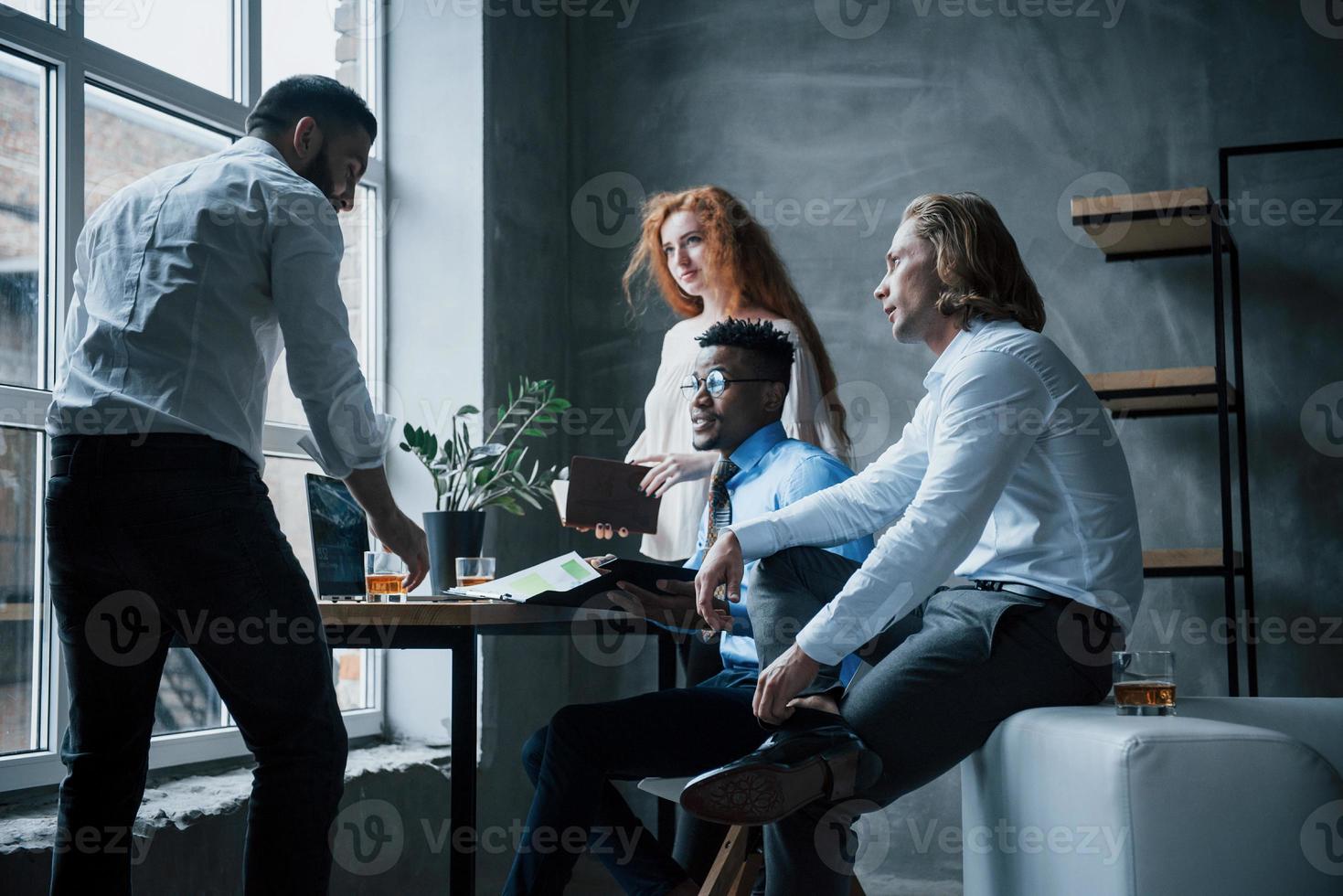 Gruppe von Büroangestellten in formeller Kleidung, die über Aufgaben und Pläne sprechen foto