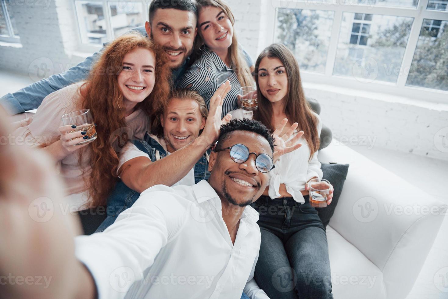 erwachsene Kinder. fröhliche junge Freunde, die Spaß haben und im weißen Interieur trinken foto