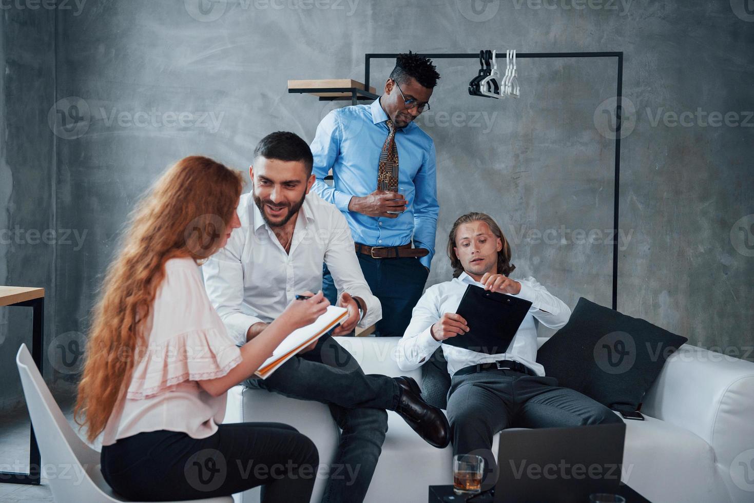 Füllen der Berichte. Gruppe gemischtrassiger Büroangestellter in formeller Kleidung, die über Aufgaben und Pläne sprechen foto