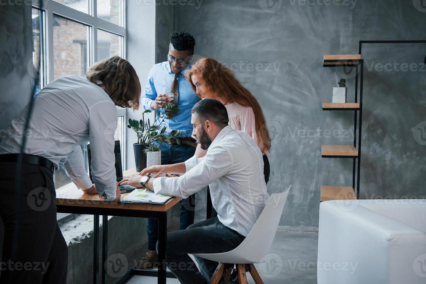 Vereinigung der Menschen. Gruppe gemischtrassiger Büroangestellter in formeller Kleidung, die über Aufgaben und Pläne sprechen foto