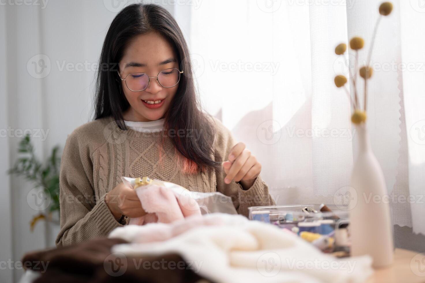 ein konzentriert jung asiatisch Frau Einfädeln ein Muster auf ein Stickerei rahmen, Handnähen auf Tuch. foto