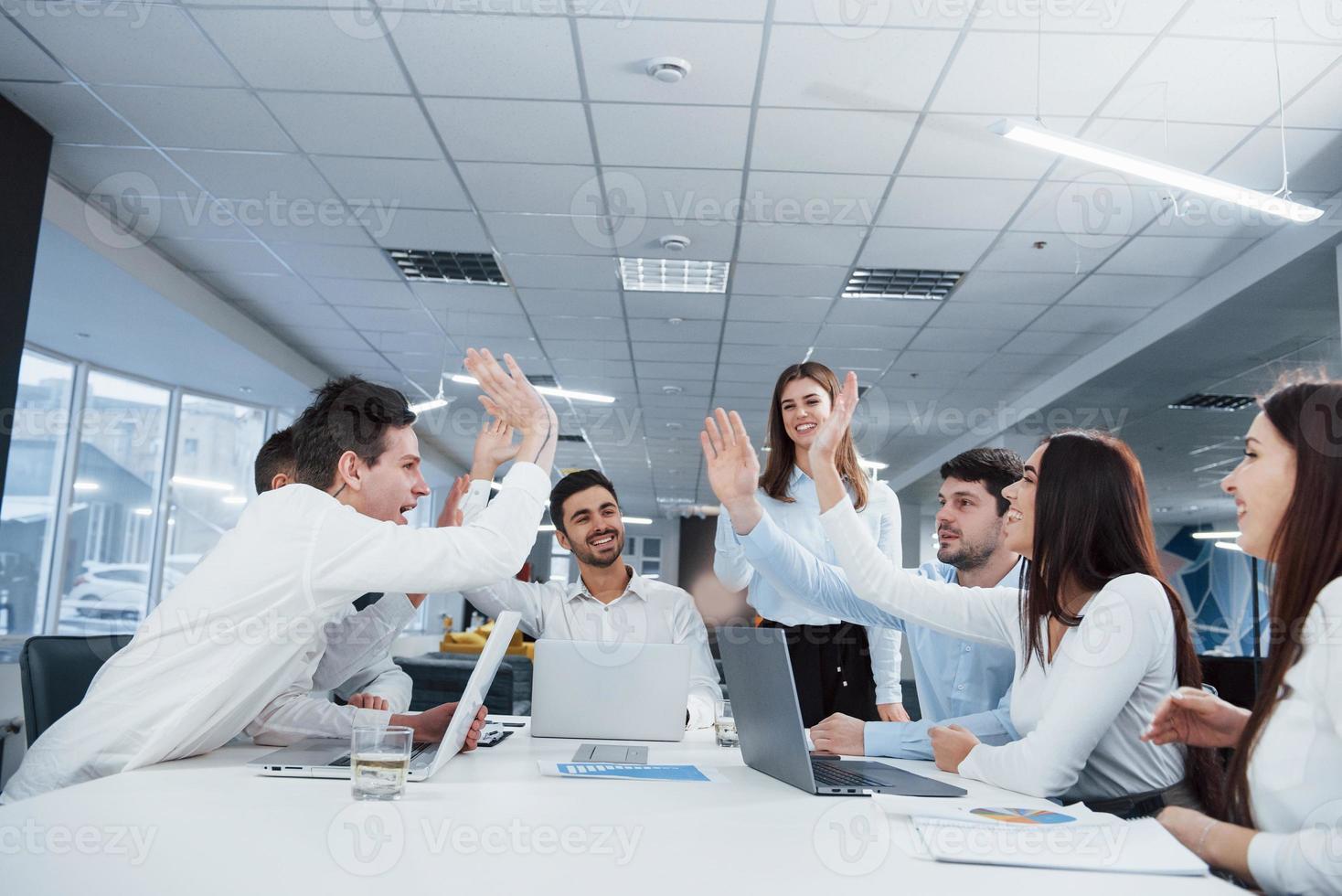 Gruppe von Büroangestellten, die glücklich sind, ihre eigenen Rekorde zu schlagen und erfolgreich zu sein foto