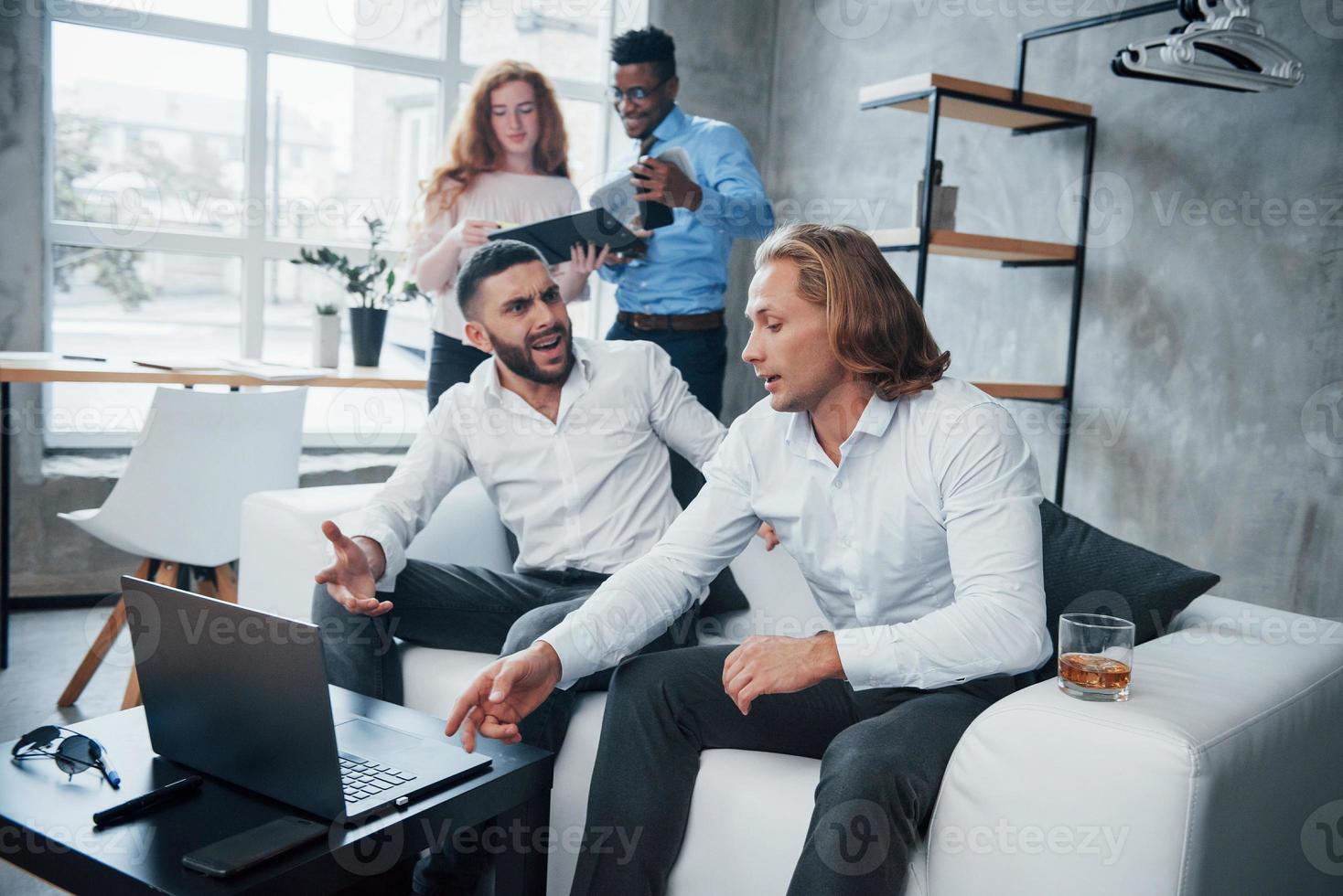 verrückte Ideen. Gruppe gemischtrassiger Büroangestellter in formeller Kleidung, die über Aufgaben und Pläne sprechen foto