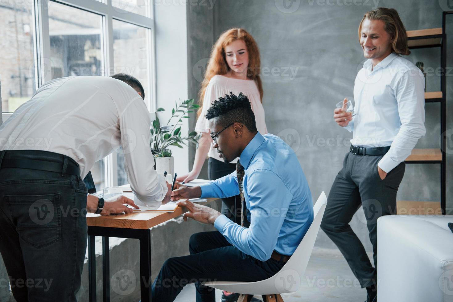 glückliche Kollegen sahen beschäftigte Leute an. Büroangestellte, die mit Arbeit beladen sind und Routineberichte schreiben foto