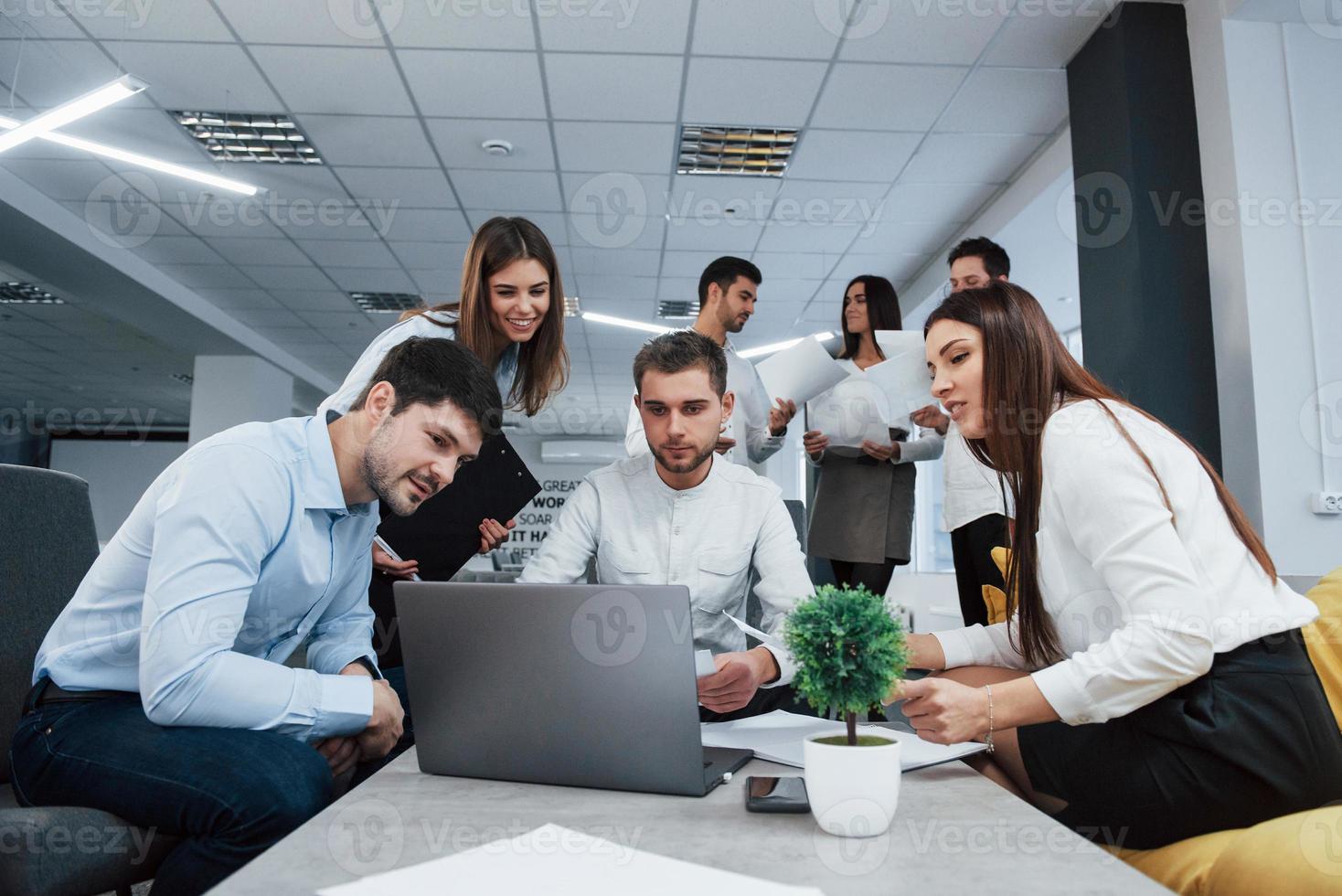 mit Laptop arbeiten. Gruppe junger Freiberufler im Büro unterhalten sich und lächeln foto