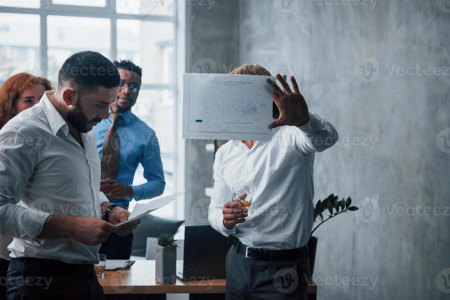 junges gemischtrassiges Team in offizieller Kleidung im Büro mit Blick auf die Preisliste foto