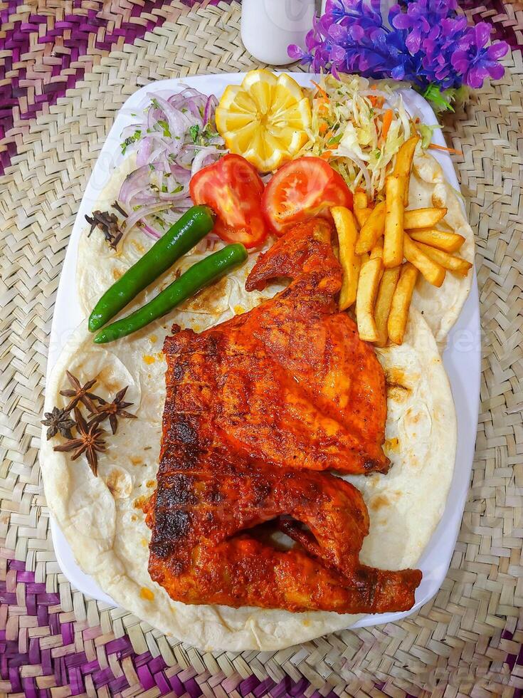 Hälfte Hähnchen Tandoori mit Fritten, Salat, Kalk, und Roti serviert im ein Gericht isoliert auf Tabelle Seite Aussicht foto