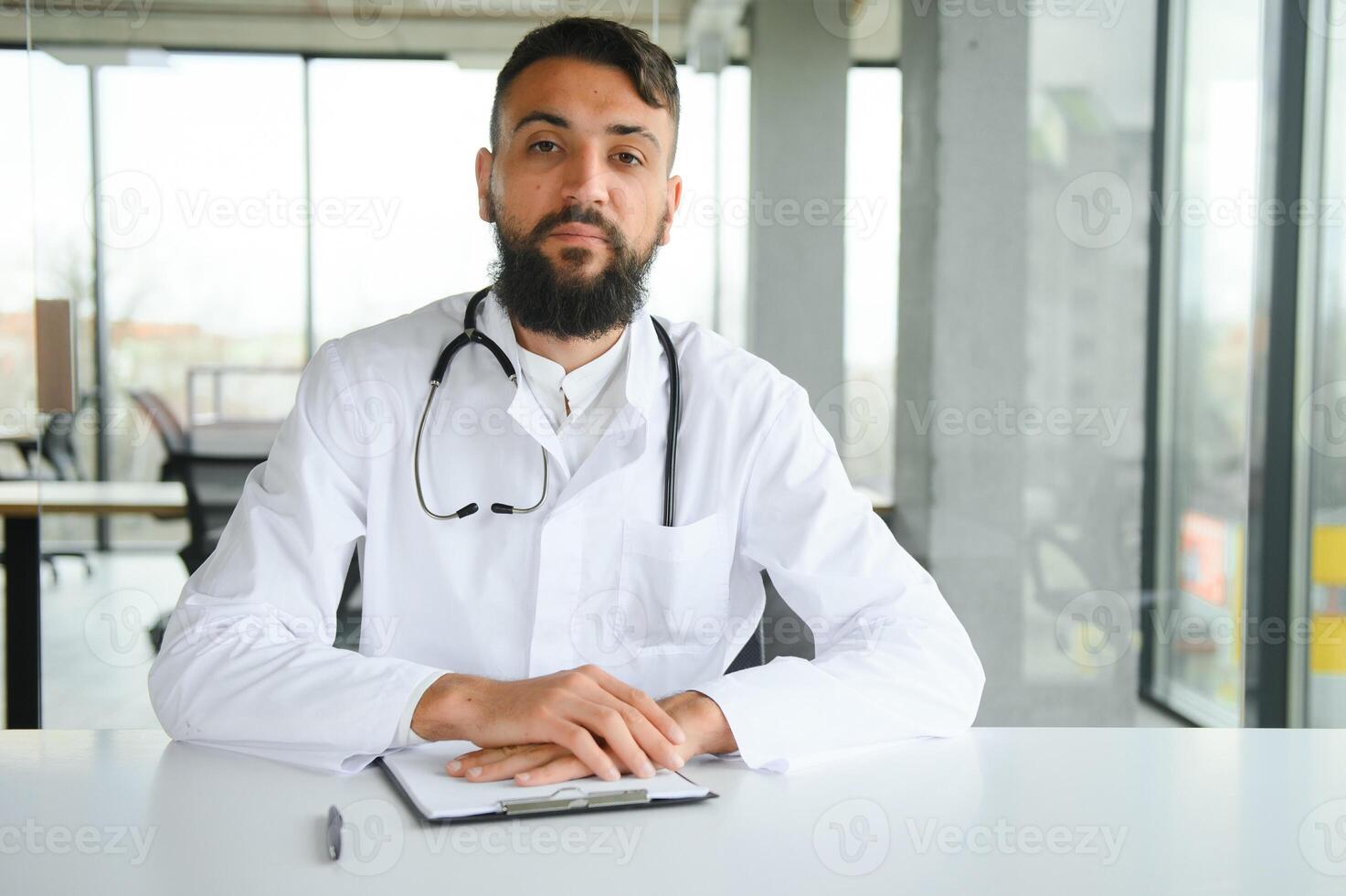 jung 30 Jahre gut aussehend angenehm Arabisch männlich Arzt im Weiß Mantel, posieren beim Kamera drinnen. foto