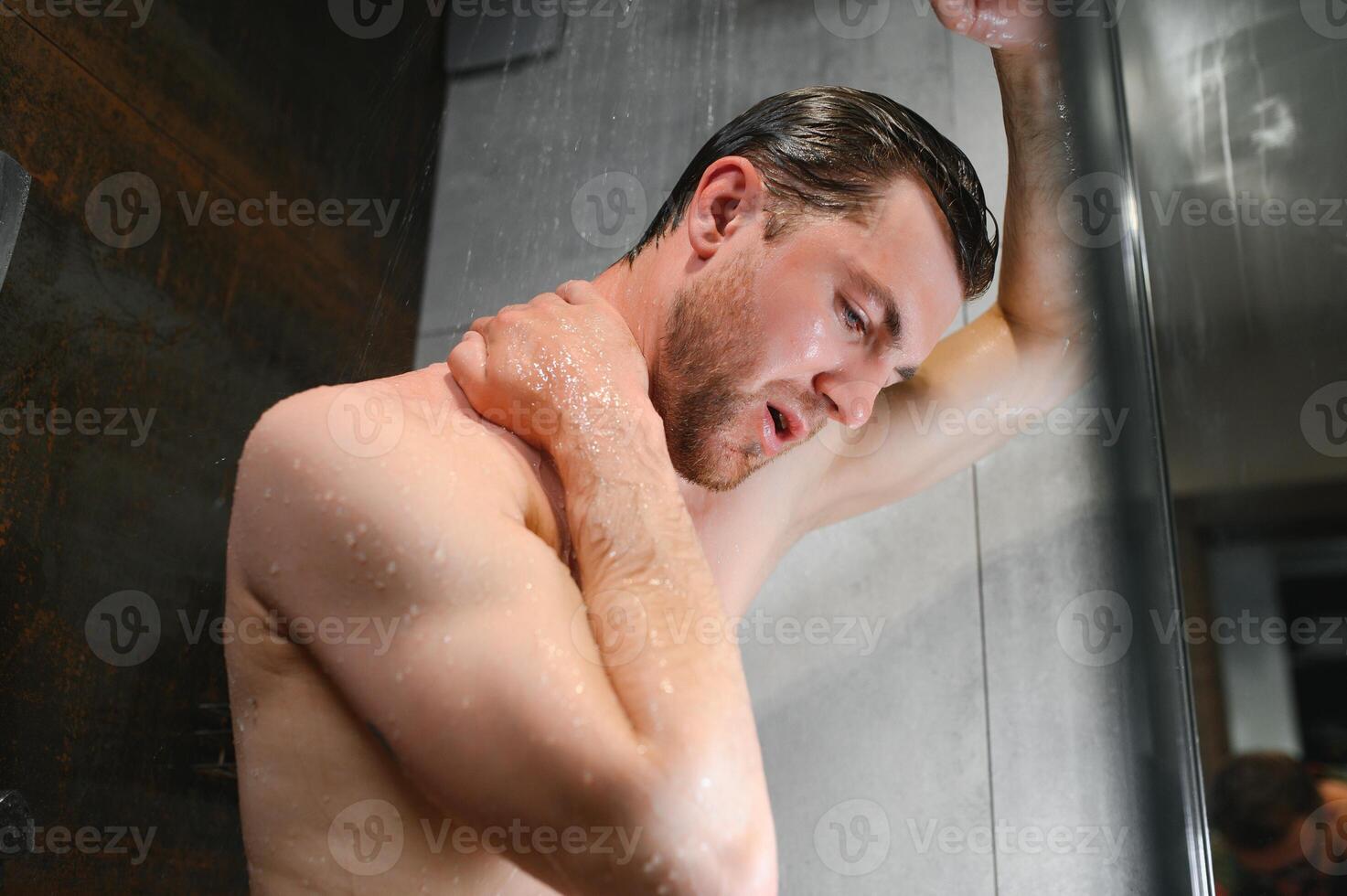 hübsch Mann nehmen Dusche im modern Badezimmer foto