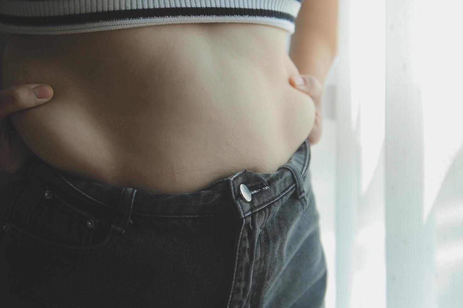 Frauen Körper Fett Bauch. fettleibig Frau Hand halten übermäßig Bauch fett. Diät Lebensstil Konzept zu reduzieren Bauch und gestalten oben gesund Bauch Muskel. foto