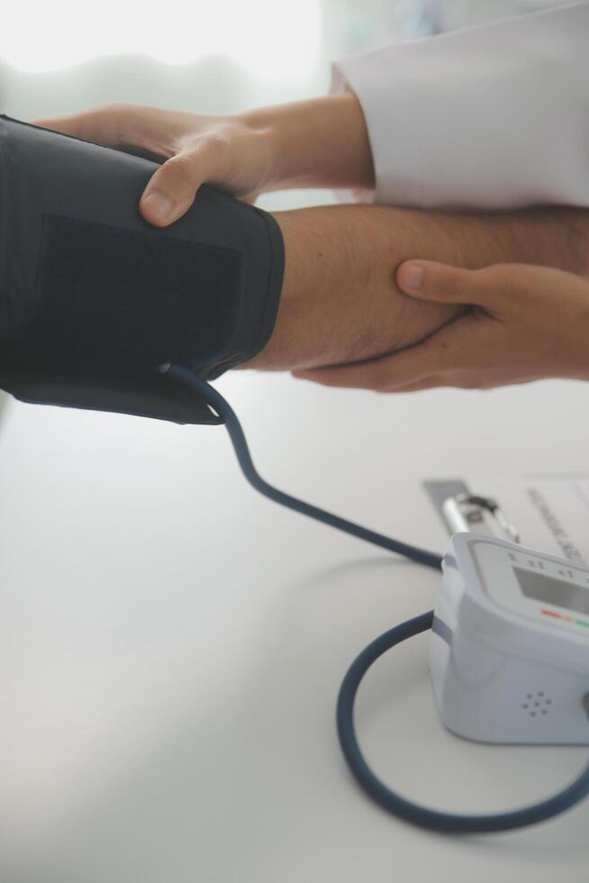 männlich Arzt Verwendet ein Blut Druck Monitor zu prüfen das Körper Druck und Impuls von das Patienten Wer Kommen Sie zu das Krankenhaus zum Kontrolluntersuchungen, medizinisch Behandlung und Gesundheit Pflege Konzept. foto