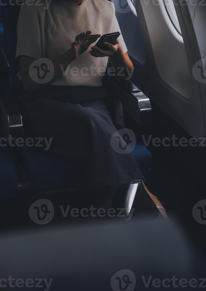 attraktiv asiatisch weiblich Passagier von Flugzeug Sitzung im komfortabel Sitz während Arbeiten Laptop und Tablette mit spotten oben Bereich mit kabellos Verbindung. Reise im Stil, Arbeit mit Anmut. foto