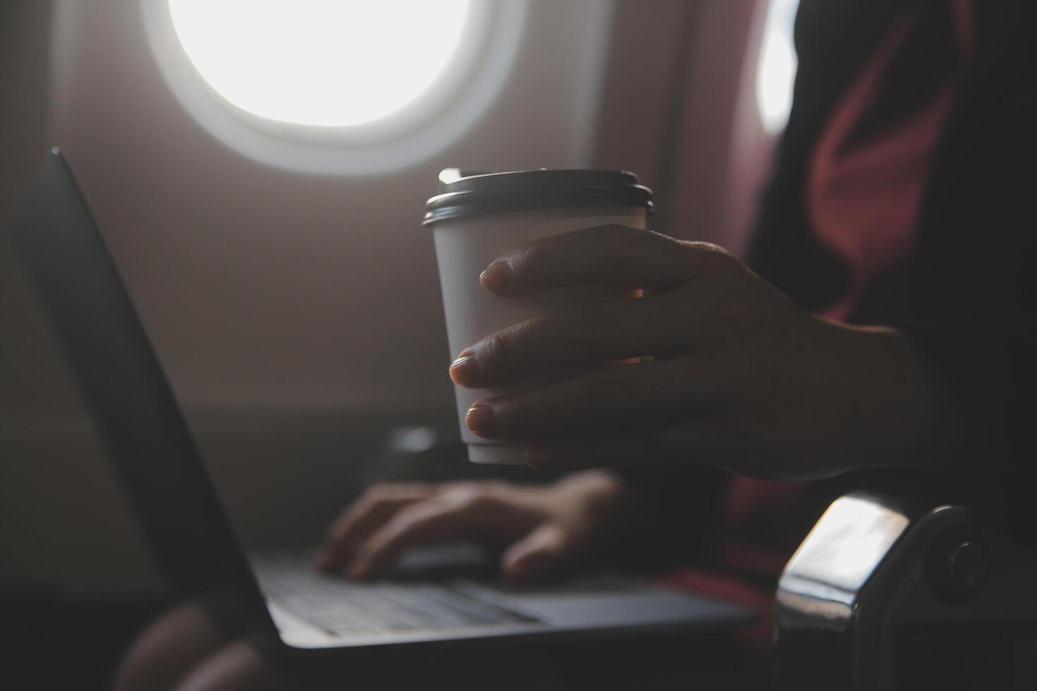 blond weiblich Tourist Überprüfung eingehend Benachrichtigung auf Smartphone Sitzung auf Sitz von Flugzeug mit Netbook.jung Geschäftsfrau Teilen Medien von Telefon auf Laptop Computer während Flugzeug Flug foto