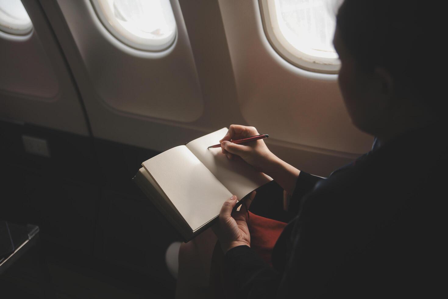 blond weiblich Tourist Überprüfung eingehend Benachrichtigung auf Smartphone Sitzung auf Sitz von Flugzeug mit Netbook.jung Geschäftsfrau Teilen Medien von Telefon auf Laptop Computer während Flugzeug Flug foto