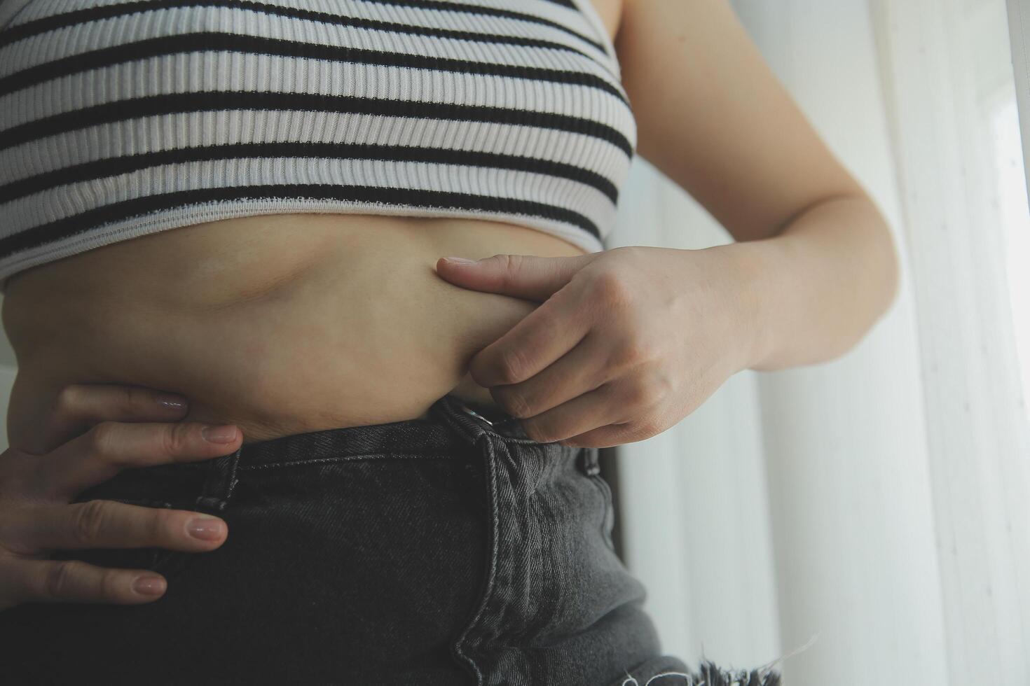 Frauen Körper Fett Bauch. fettleibig Frau Hand halten übermäßig Bauch fett. Diät Lebensstil Konzept zu reduzieren Bauch und gestalten oben gesund Bauch Muskel. foto