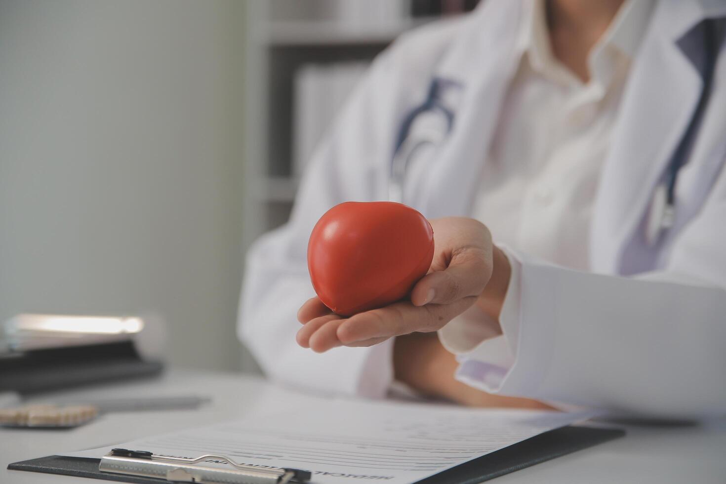 Hände von Arzt Frau halten rot Herz, zeigen Symbol von Liebe, Mensch Unterstützung zu geduldig, fördern medizinisch Versicherung, früh Untersuchung zum Gesundheitspflege, Kardiologe Hilfe. schließen oben von Objekt foto