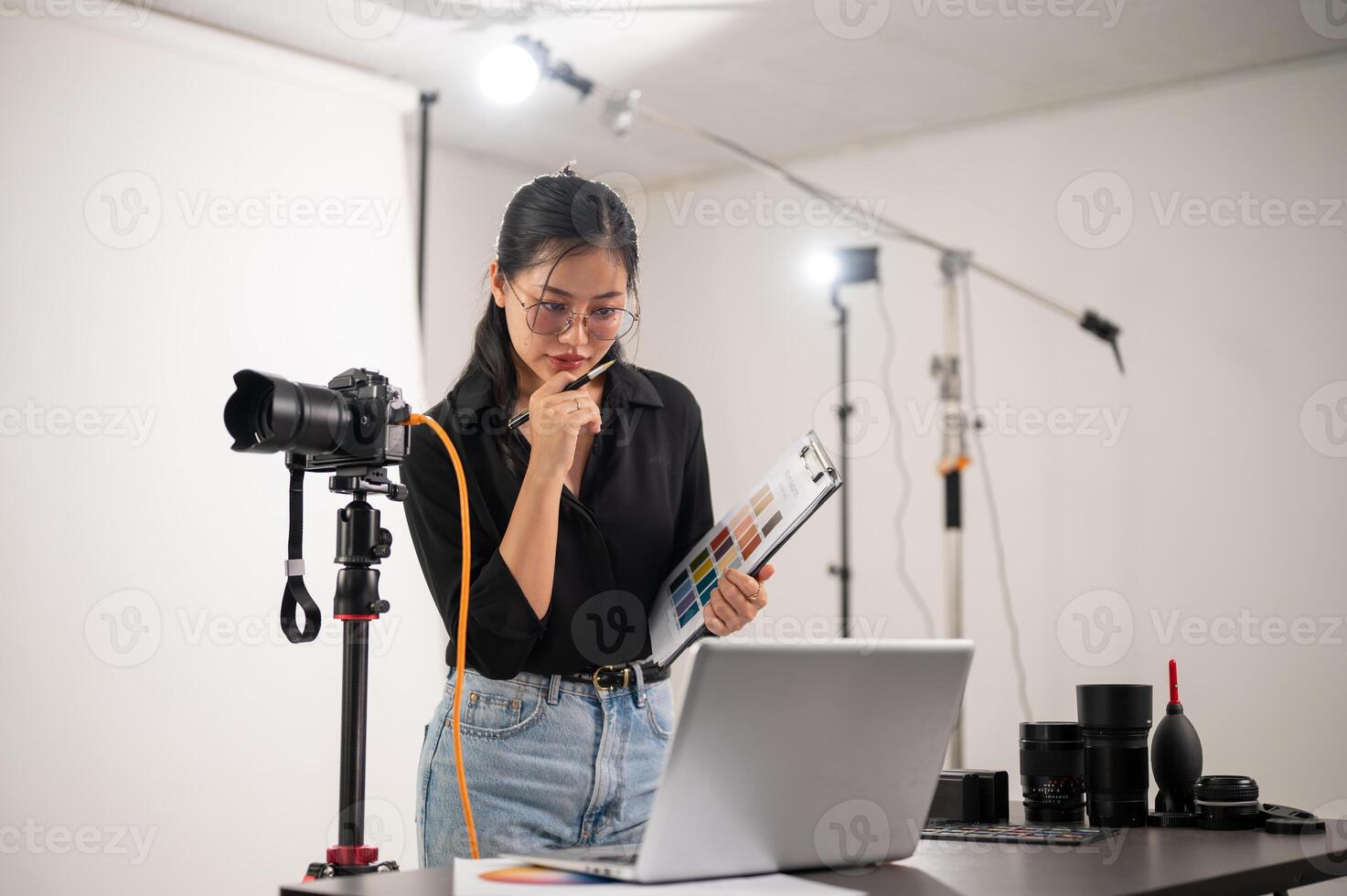 ein Cool, attraktiv asiatisch weiblich Fotograf Produzent ist Arbeiten im ein Schießen Studio. foto