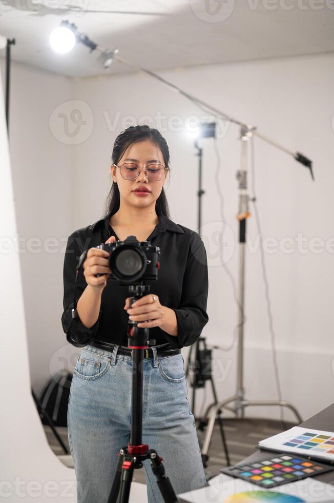 ein Fachmann asiatisch weiblich Fotograf ist einstellen ihr dslr Kamera auf ein Stativ Stand. foto