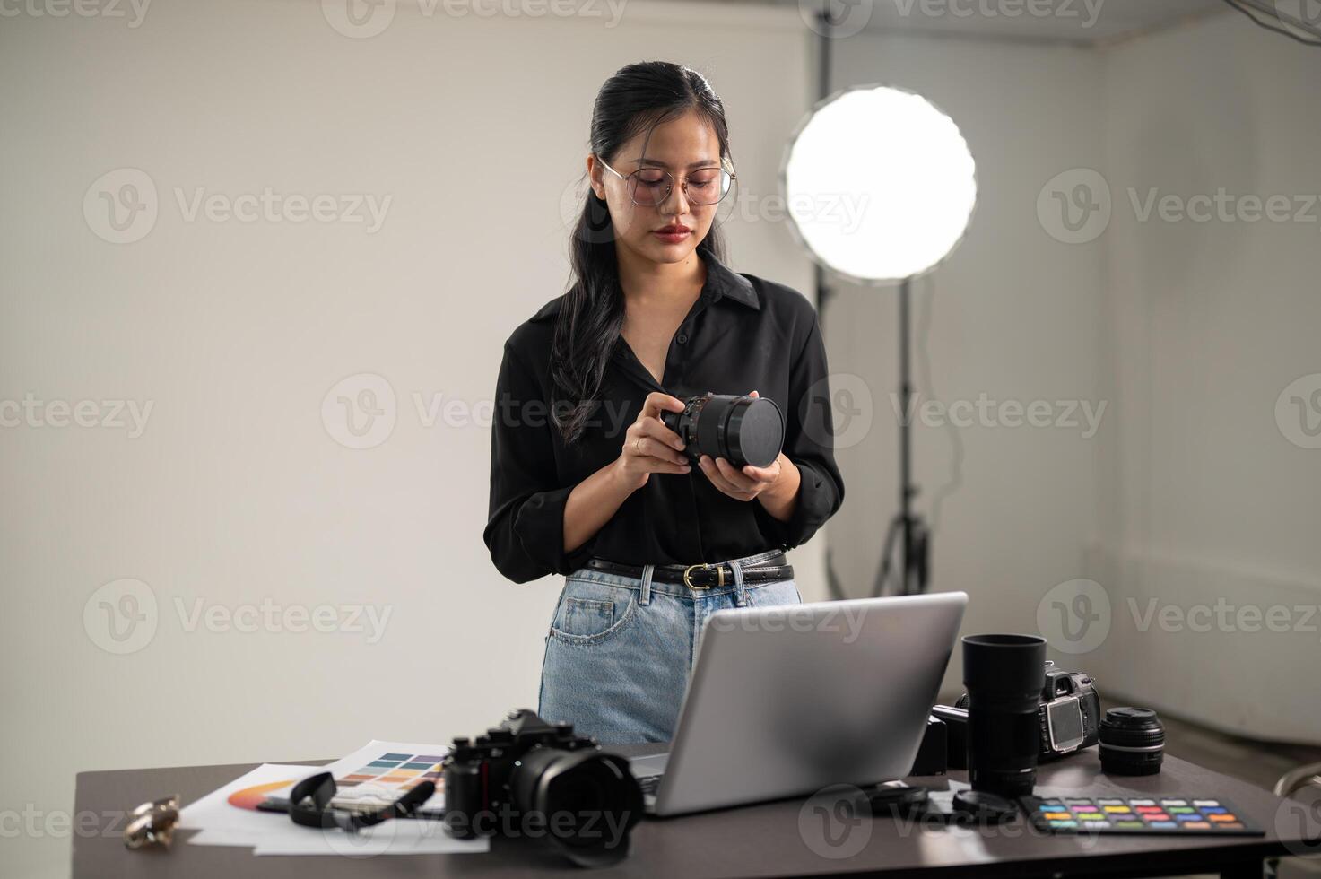 Fachmann asiatisch weiblich Fotograf ist vorbereiten ihr Kamera zum ein Foto-Shooting, Arbeiten im ein Studio foto