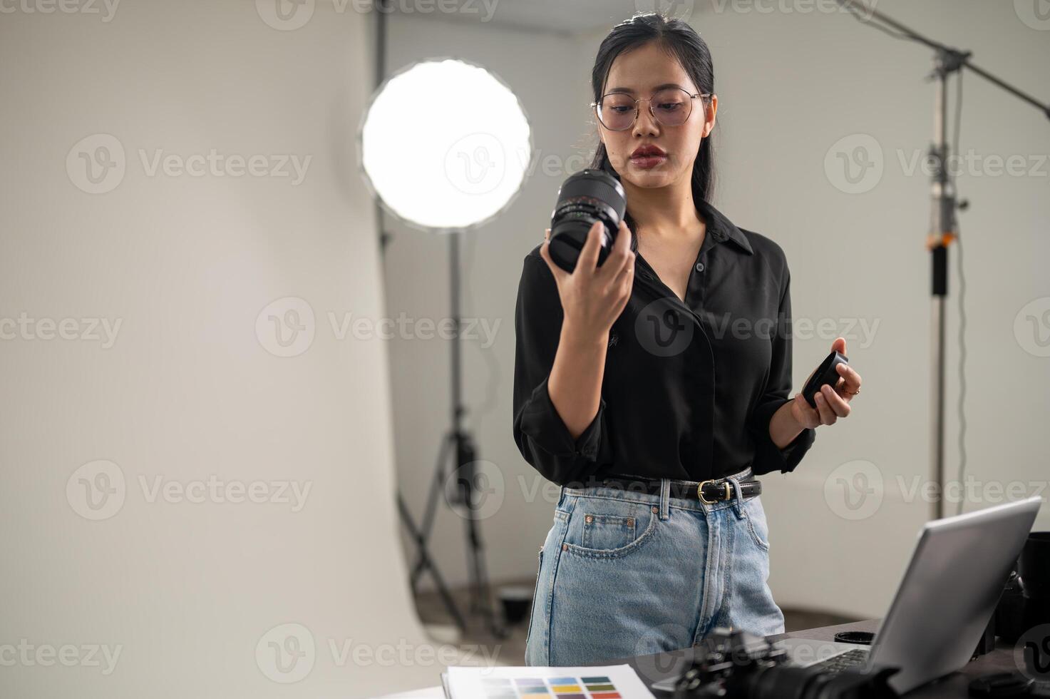 Fachmann asiatisch weiblich Fotograf ist vorbereiten ihr Kamera zum ein Foto-Shooting, Arbeiten im ein Studio foto