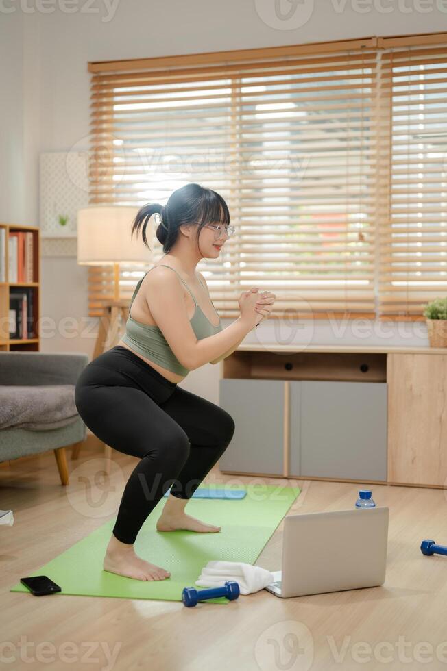 ein gesund, stark asiatisch Frau im Sportbekleidung ist tun ein Kader auf ein Yoga Matte, Arbeiten aus beim heim. foto