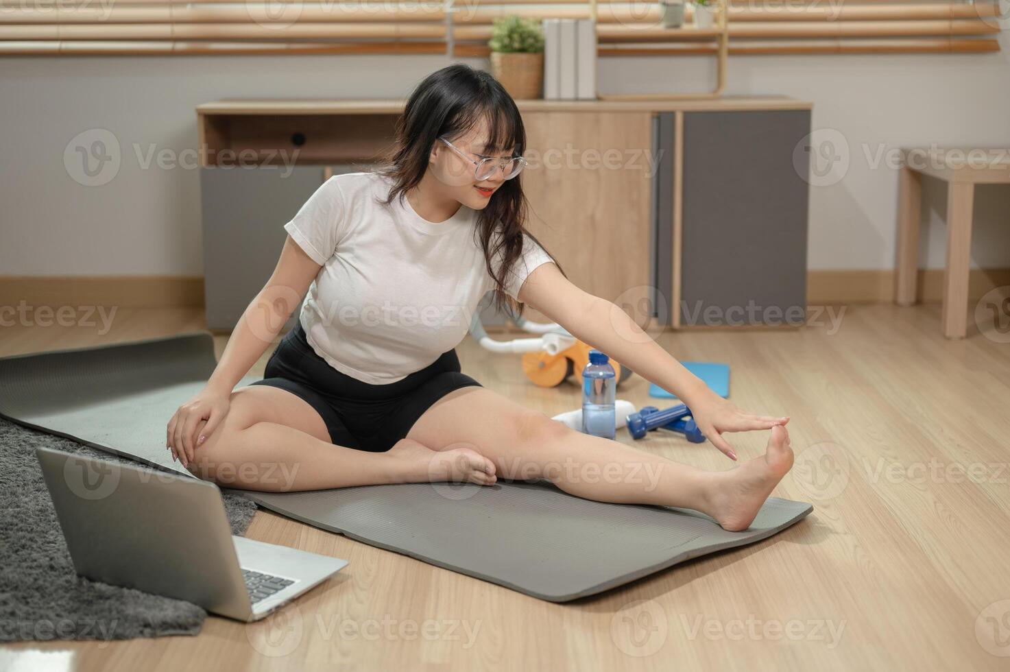 ein passen asiatisch Frau im Sportbekleidung ist tun Yoga beim heim, folgenden das Yoga Lernprogramm online. foto
