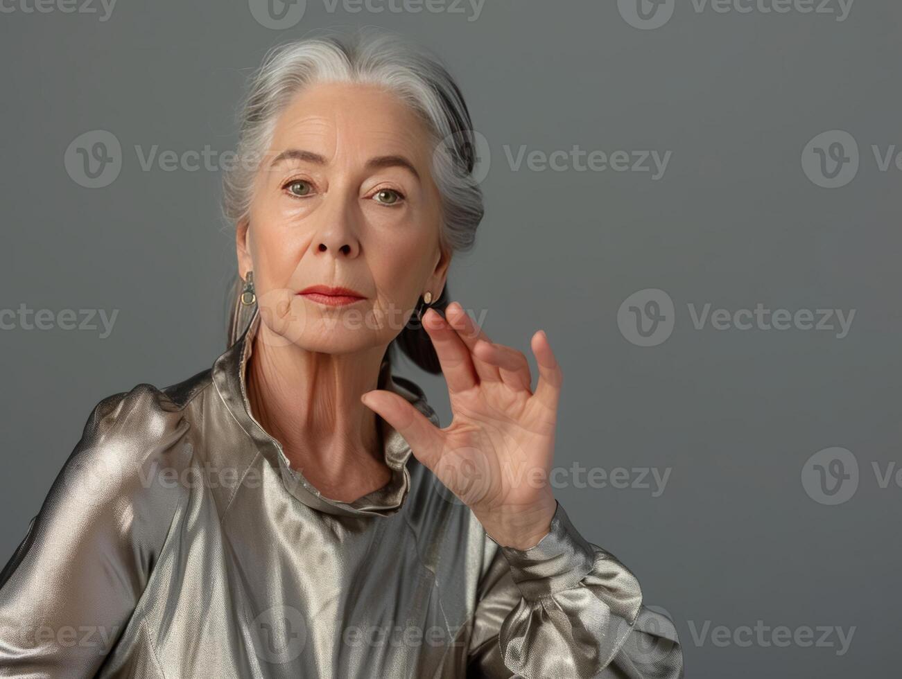 ein Frau mit grau Haar trägt Silber Hemd und Ohrringe foto