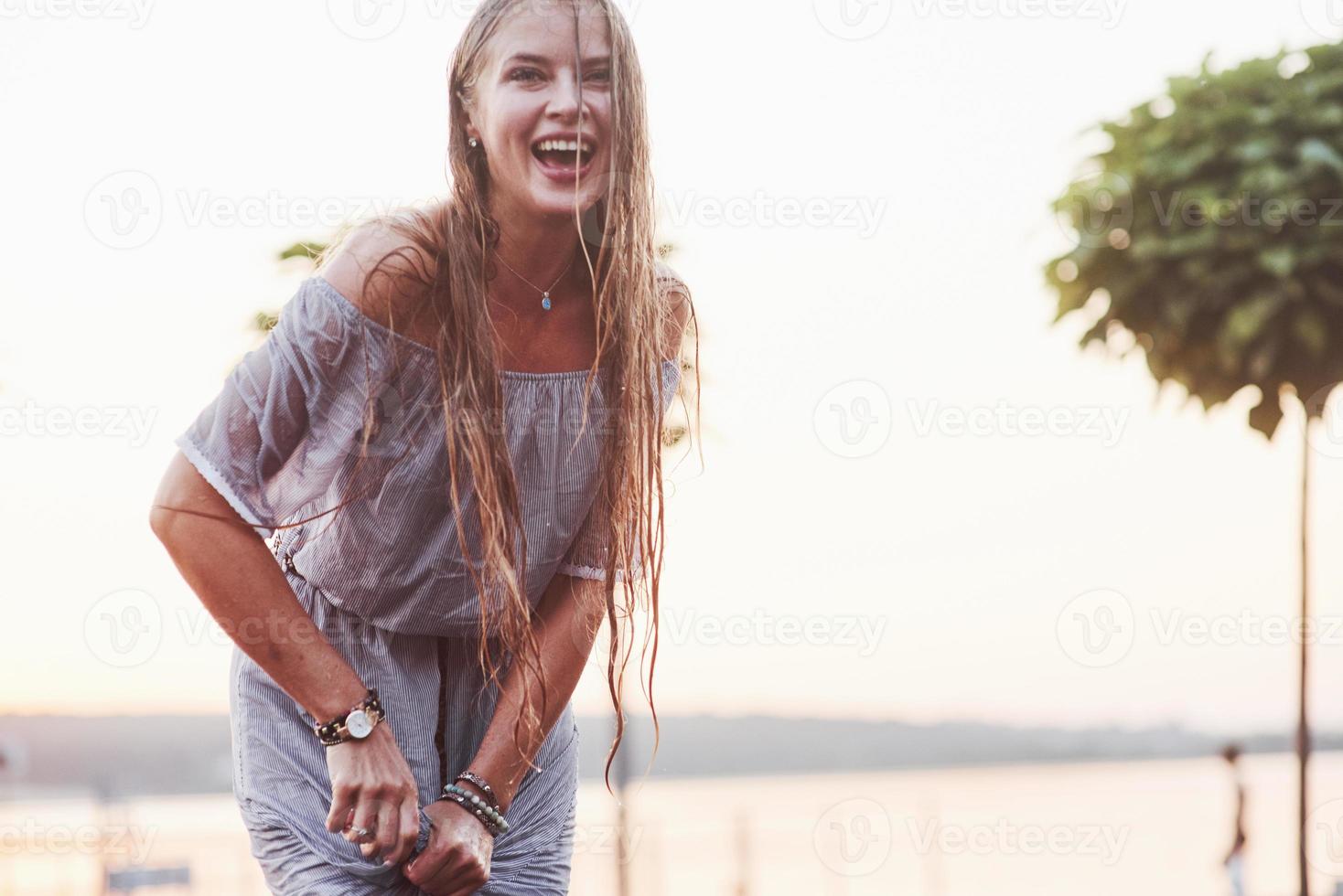 Frauen erfrischen sich an sonnigen heißen Tagen mit Springbrunnen im Hintergrund von See und Wald foto