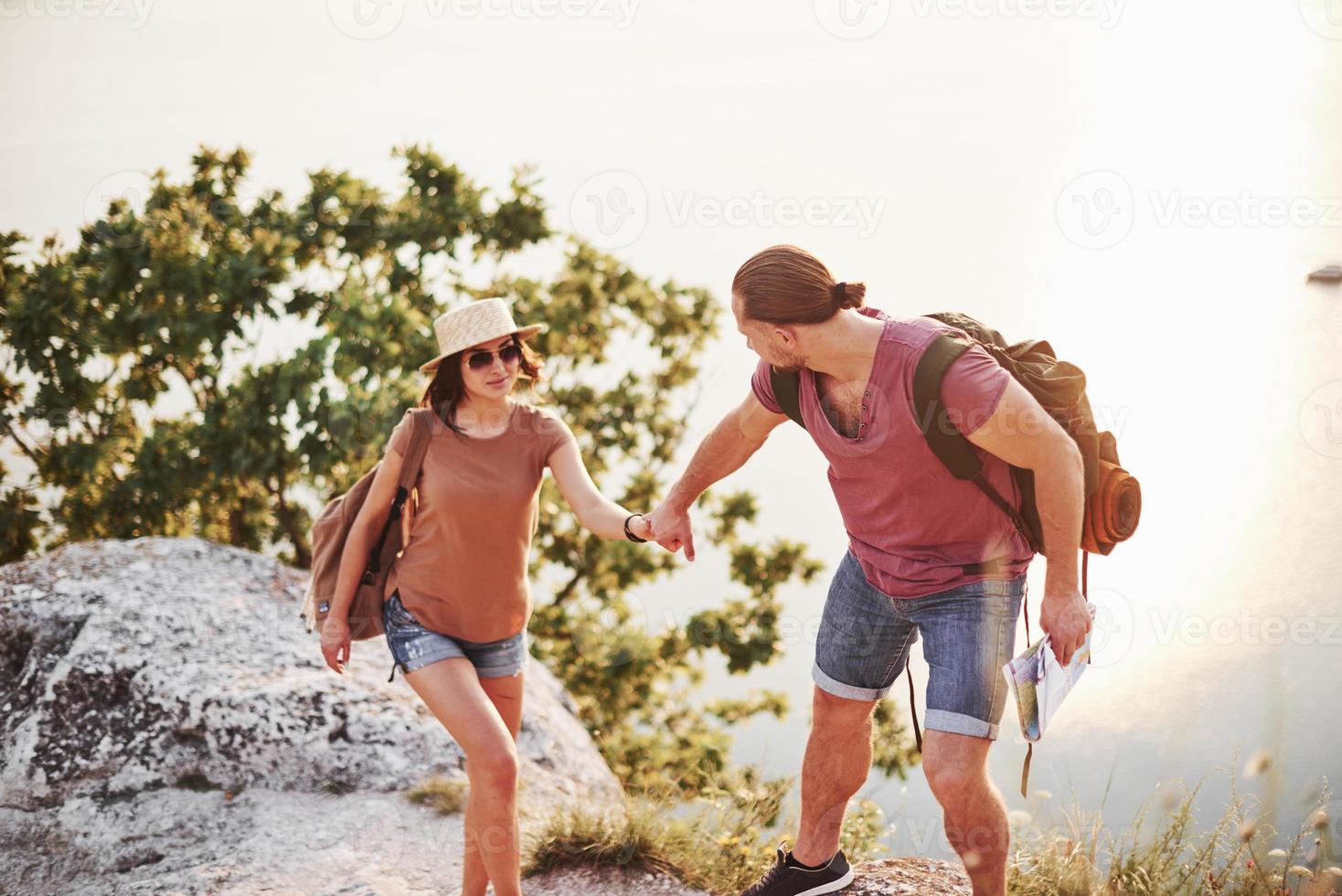 aushelfen. junges Paar hat beschlossen, seinen Urlaub aktiv am Rande des wunderschönen Felsens mit See im Hintergrund zu verbringen foto