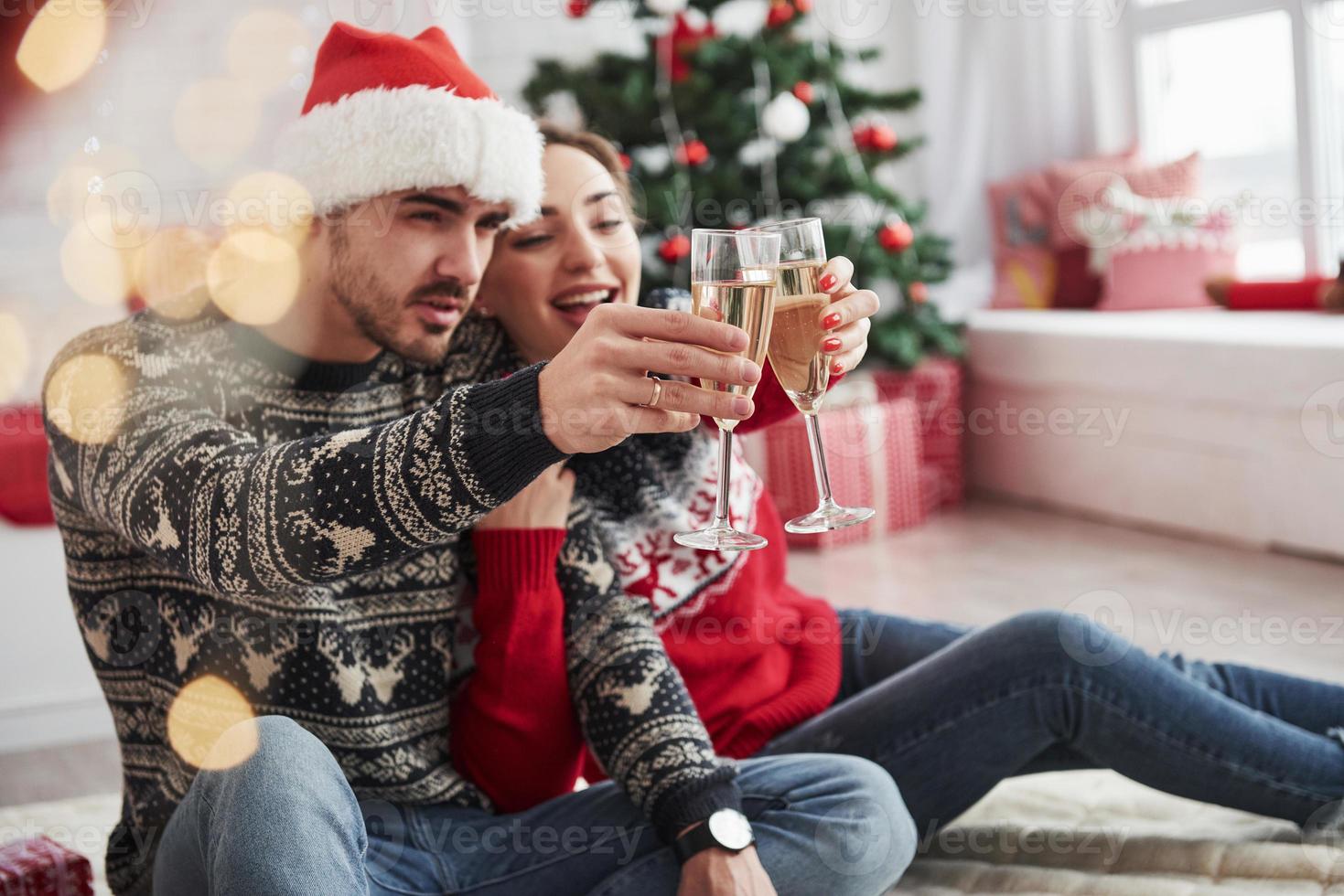 einen Toast machen. zwei menschen sitzen auf dem boden und feiern neujahr foto