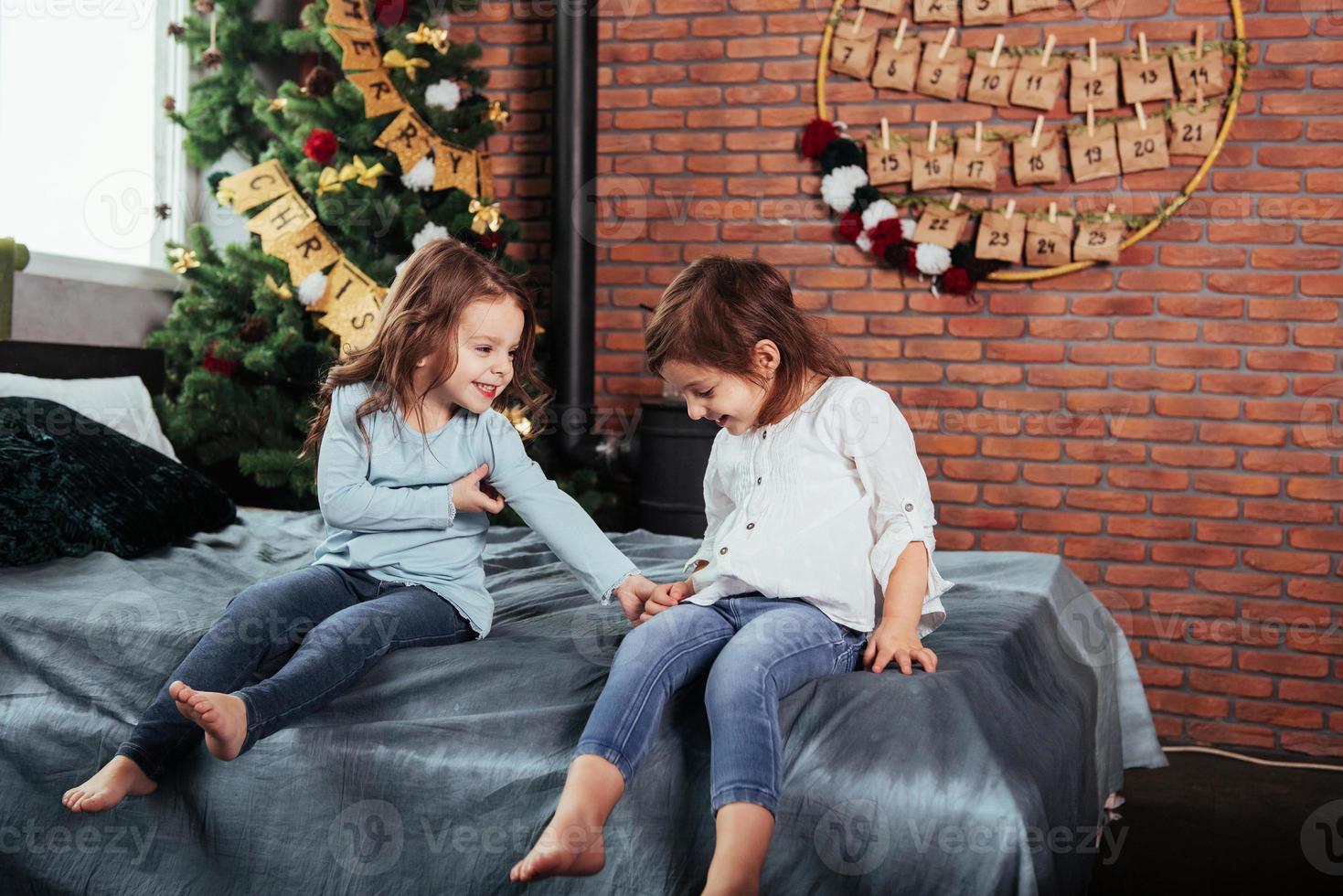 Kind lächelt. Kinder sitzen auf dem Bett mit dekorativem Hintergrund. Vorstellung des neuen Jahres foto