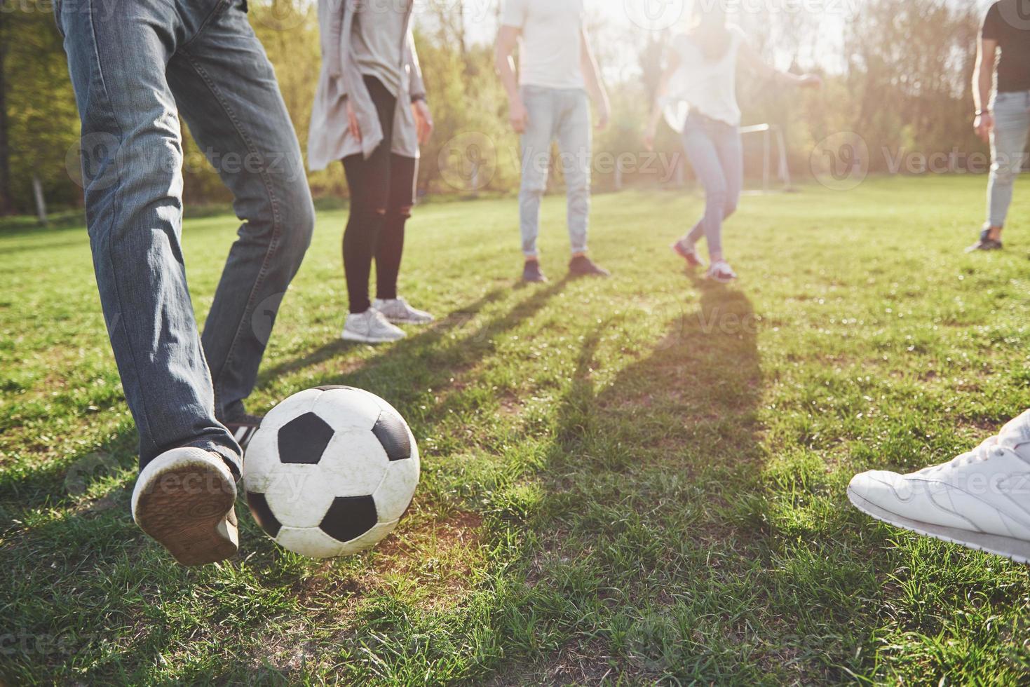 eine Gruppe von Freunden in legerem Outfit spielt Fußball unter freiem Himmel. Leute haben Spaß und haben Spaß. aktive Erholung und malerischer Sonnenuntergang foto