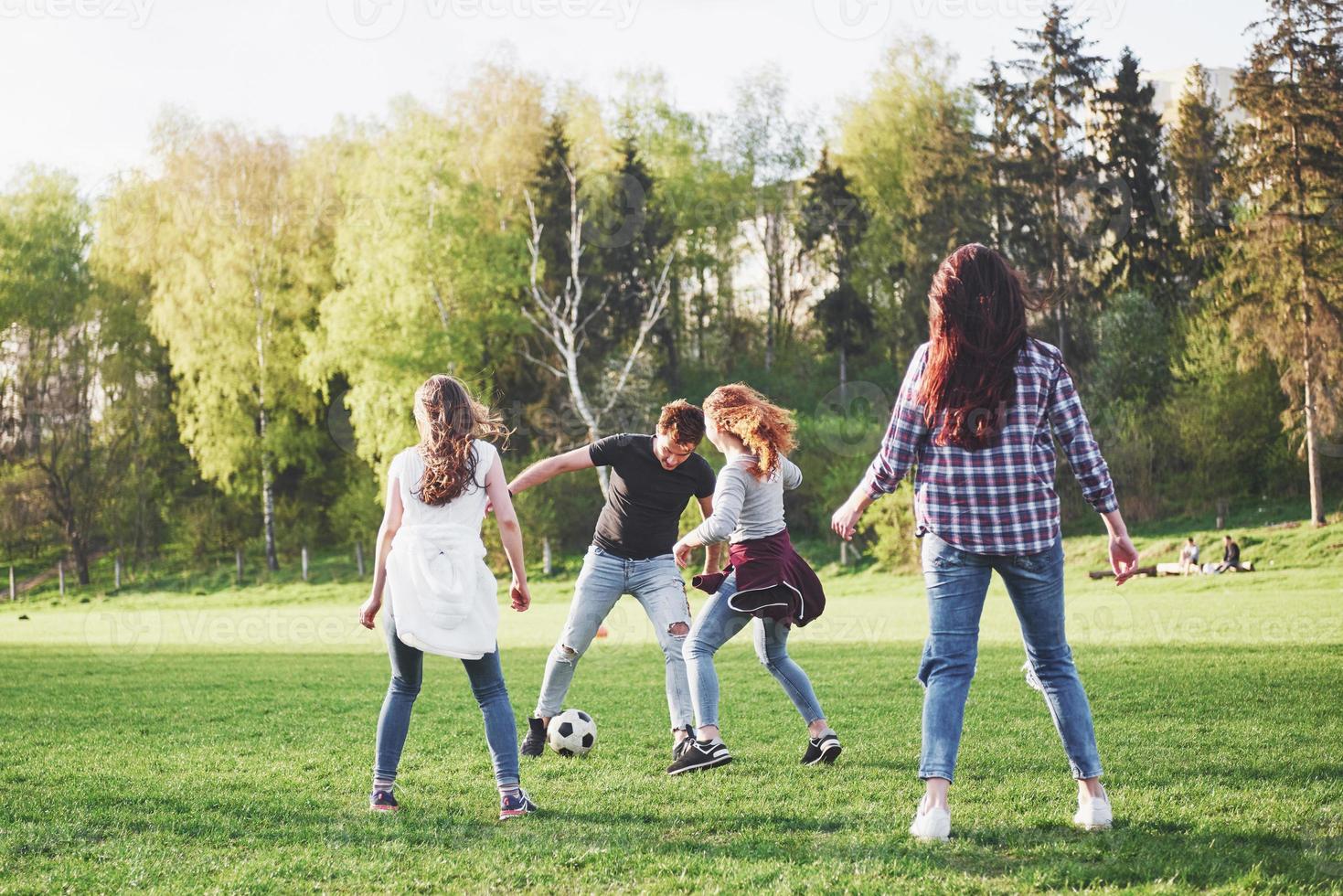 eine Gruppe von Freunden in legerem Outfit spielt Fußball unter freiem Himmel. Leute haben Spaß und haben Spaß. aktive Erholung und malerischer Sonnenuntergang foto