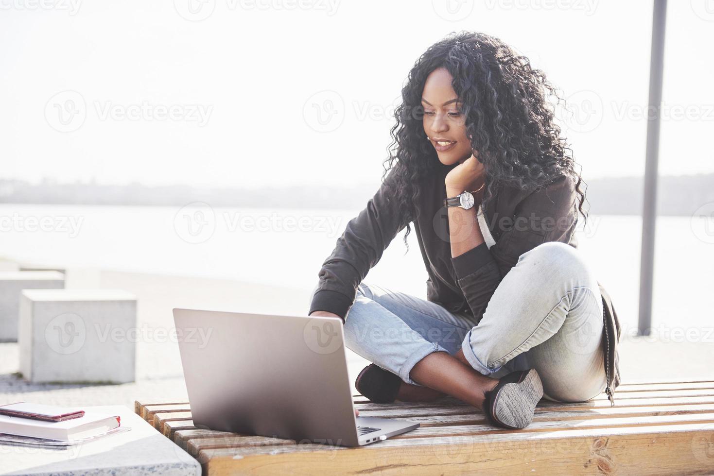 junge Frau auf der Straße, die am Laptop arbeitet foto