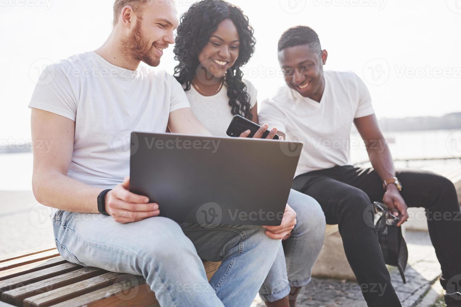 schöne multiethnische Freunde mit einem Laptop auf der Straße. Jugend-Lifestyle-Konzept foto