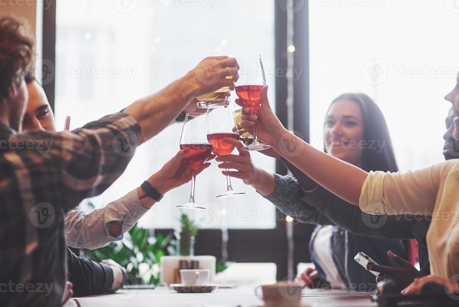 Gruppe junger Freunde, die Spaß haben und lachen, während sie im Restaurant am Tisch speisen? foto