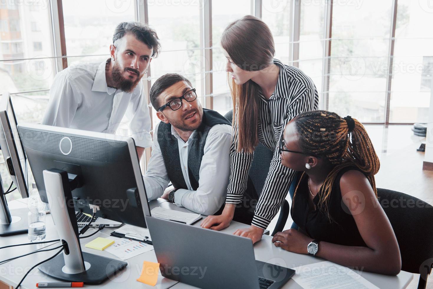 Junge Mitarbeiter, die im Büro am Tisch sitzen und einen Laptop verwenden, ein Teamwork-Brainstorming-Meeting-Konzept. foto