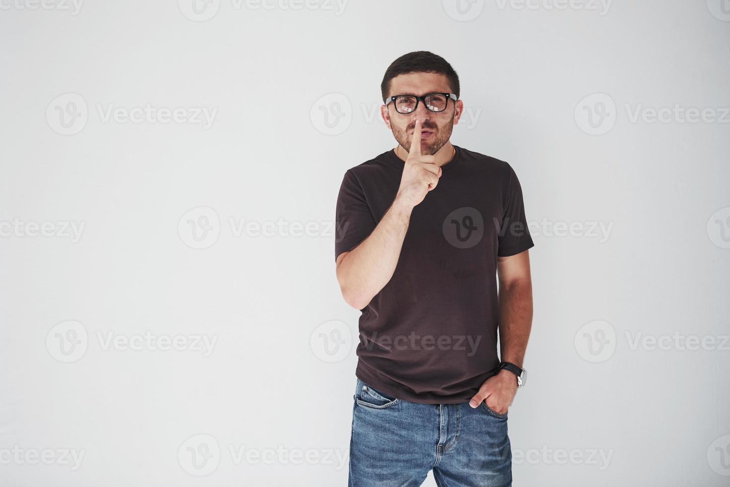 junger lässiger Mann über weißem Hintergrund Wand bittet, mit dem Finger auf den Lippen ruhig zu sein. Stille und geheimes Konzept foto