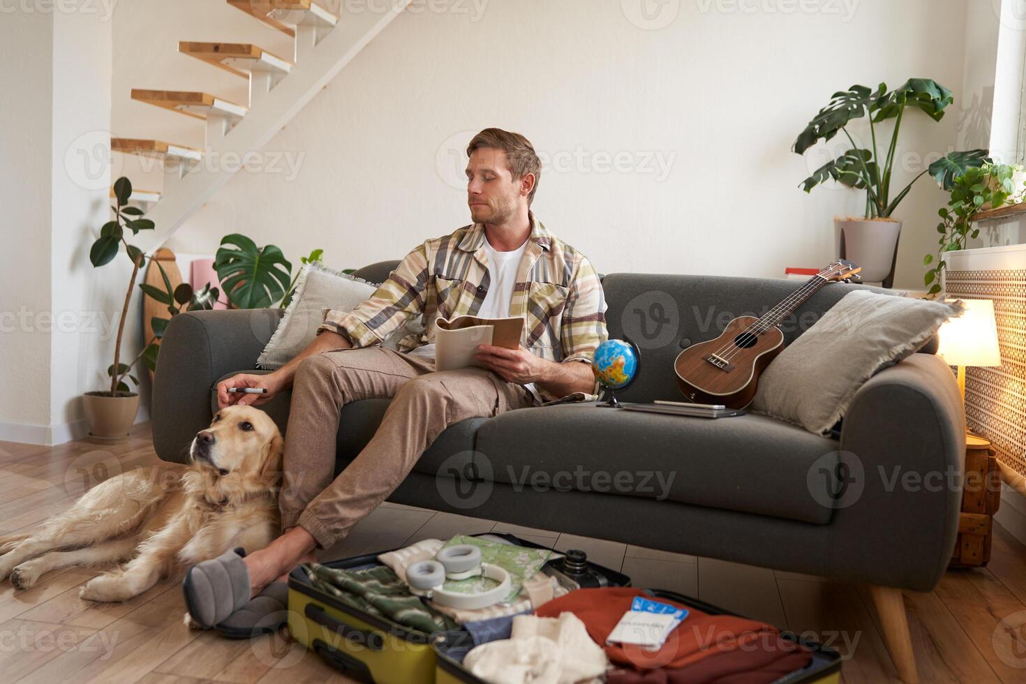 Porträt von Mann Sitzung mit seine Hund, Verpackung Koffer zum ein Urlaub, gehen auf Ausflug mit ein Haustier foto